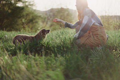 Side view of woman sitting on grassy field