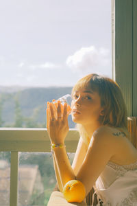 Portrait of woman drinking water from railing