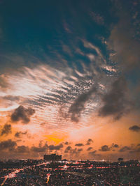 Aerial view of illuminated city against sky during sunset