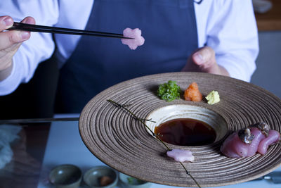 Midsection of chef holding meal in plate