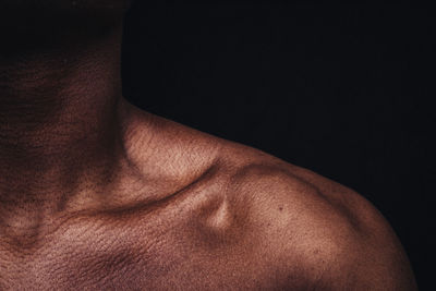 Close-up of shirtless man against black background