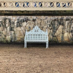 Empty bench against building wall