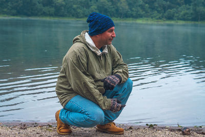 Man looking away while sitting by lake