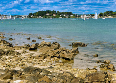 Rocks on beach by sea against sky