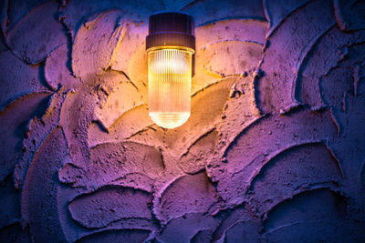 Close-up of illuminated light bulb against wall