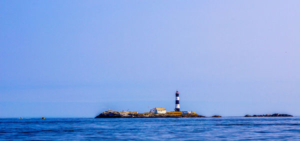 Lighthouse on island against sky