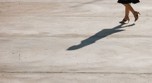 Low section of woman with shadow on concrete