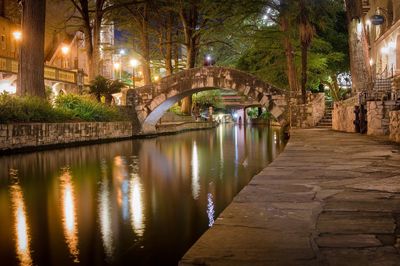 Illuminated bridge over water in city at night