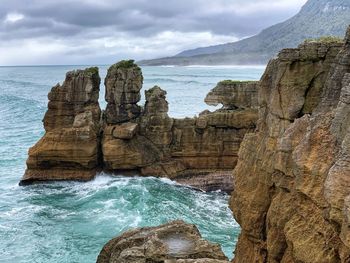 Rock formation on sea shore against sky