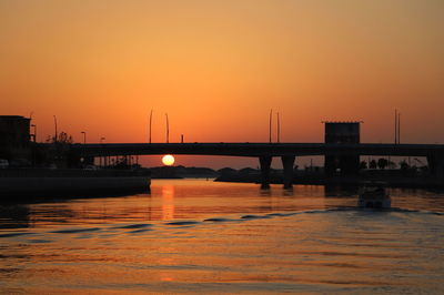 Bridge over river against orange sky