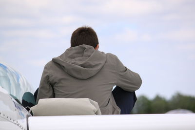 Rear view of man on airplane against sky