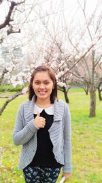 Portrait of a smiling young woman standing against plants