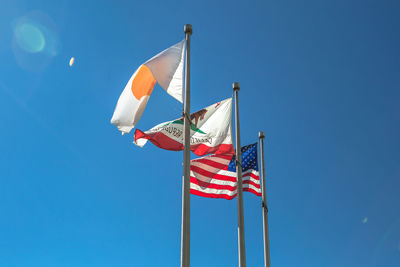 Low angle view of flags against clear blue sky