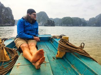 Young man sitting on boat in lake