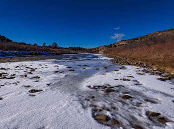 Surface level of snow snowy frozen river against clear blue sky