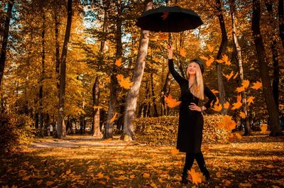 Full length of woman standing by trees during autumn