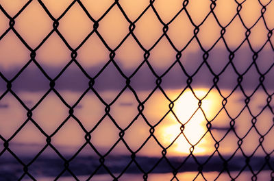 Close-up of chainlink fence at sunset