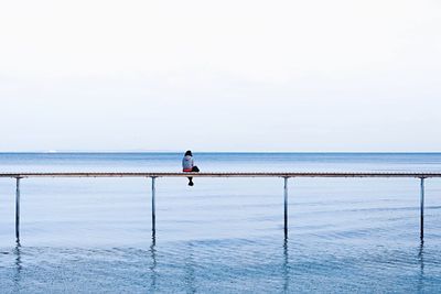 Man standing in sea against clear sky