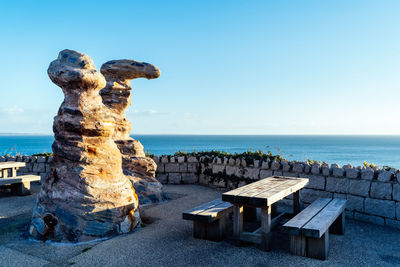 Stack of rocks on beach against clear blue sky