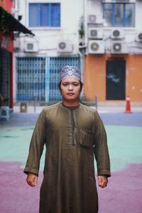 Portrait of young man standing against building