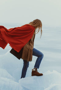 Low section of woman standing on snow against sky