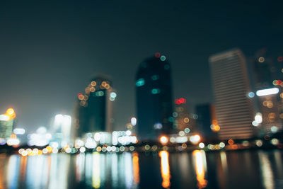 Defocused image of illuminated buildings against sky at night