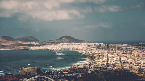 Aerial view of cityscape by sea against sky