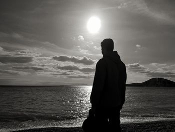 Silhouette man standing on beach against sky