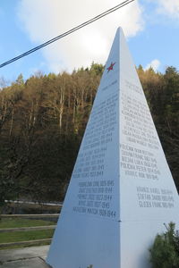 Information sign by tree against sky