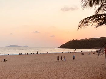 People on beach against sky during sunset