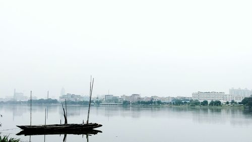 Boats in calm sea against clear sky