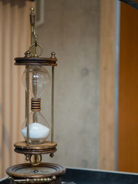 Close-up of hourglass on table against wall