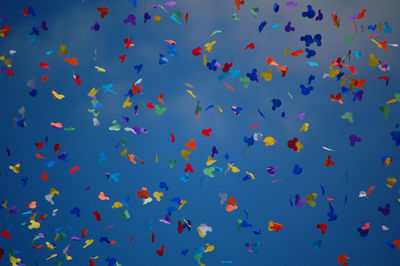 Low angle view of colorful confetti against blue sky
