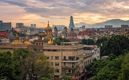 Buildings in city against sky during sunset