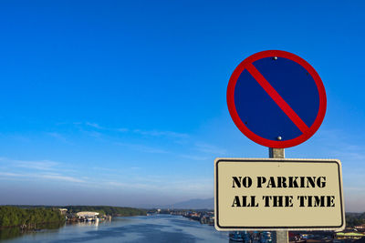 Information sign by road against blue sky