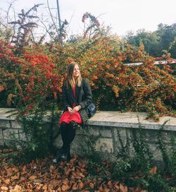 Full length portrait of smiling young woman during autumn