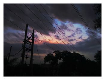 Low angle view of silhouette electricity pylon against sky