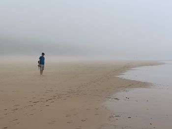 Rear view of man on beach against sky