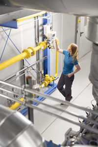 Technician standing with hand in pocket working at factory