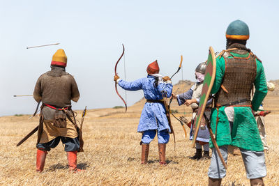 Rear view of people standing on field against clear sky