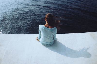 High angle view of woman sitting on pier at sea