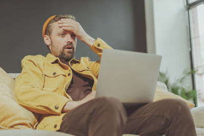 Man using laptop while sitting on sofa at home