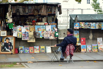 Full length of man sitting on multi colored umbrellas