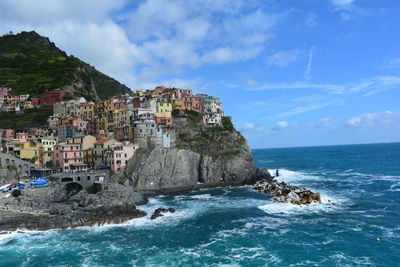 Manarola at sea shore against sky