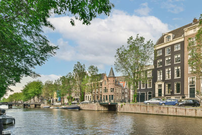 Buildings by river against sky