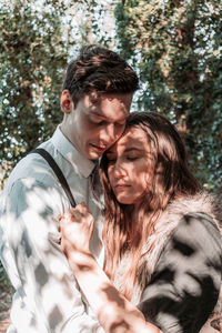 Young couple kissing against trees