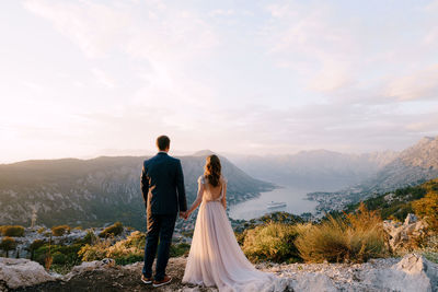 Rear view of friends standing on mountain against sky