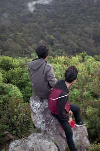 Rear view of man and woman standing on rock