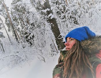 Young woman standing by tree during winter