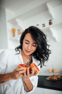 Smiling woman holding blood orange at kitchen